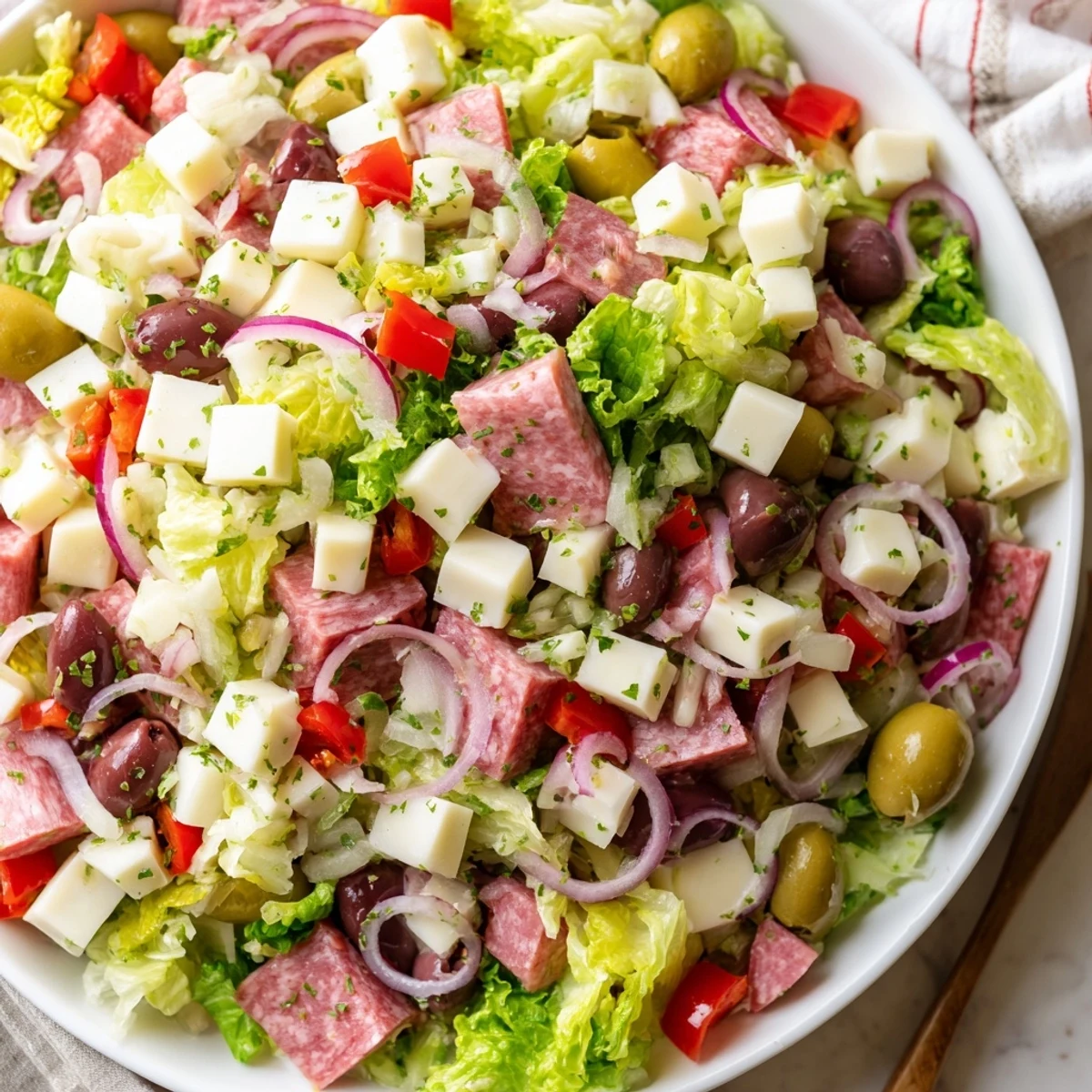 Fresh New Orleans Muffuletta Salad with olives, cured meats, cheeses, and tangy dressing served over crisp romaine.  