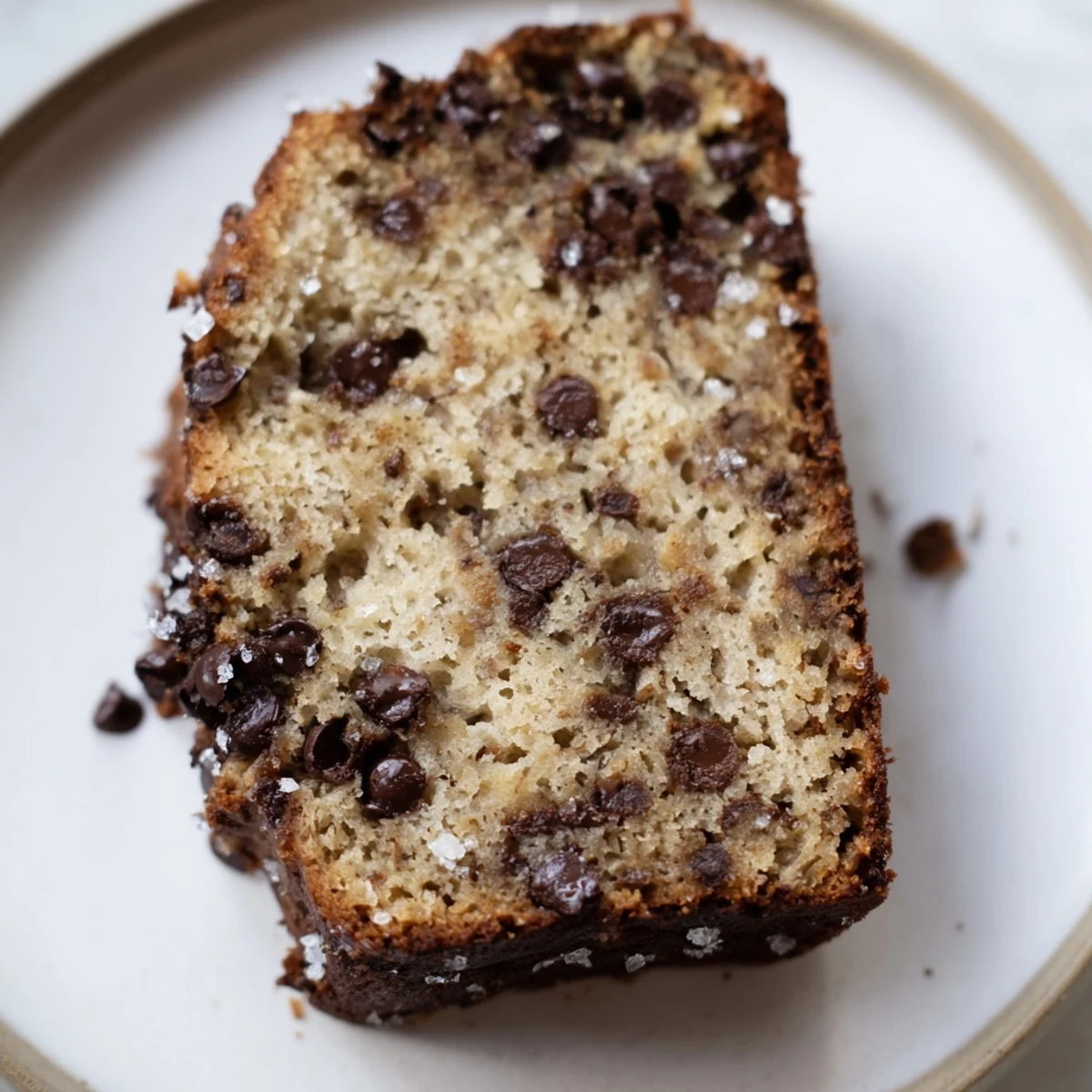 A warm slice of chocolate chip banana bread loaf served with coffee for a cozy breakfast.