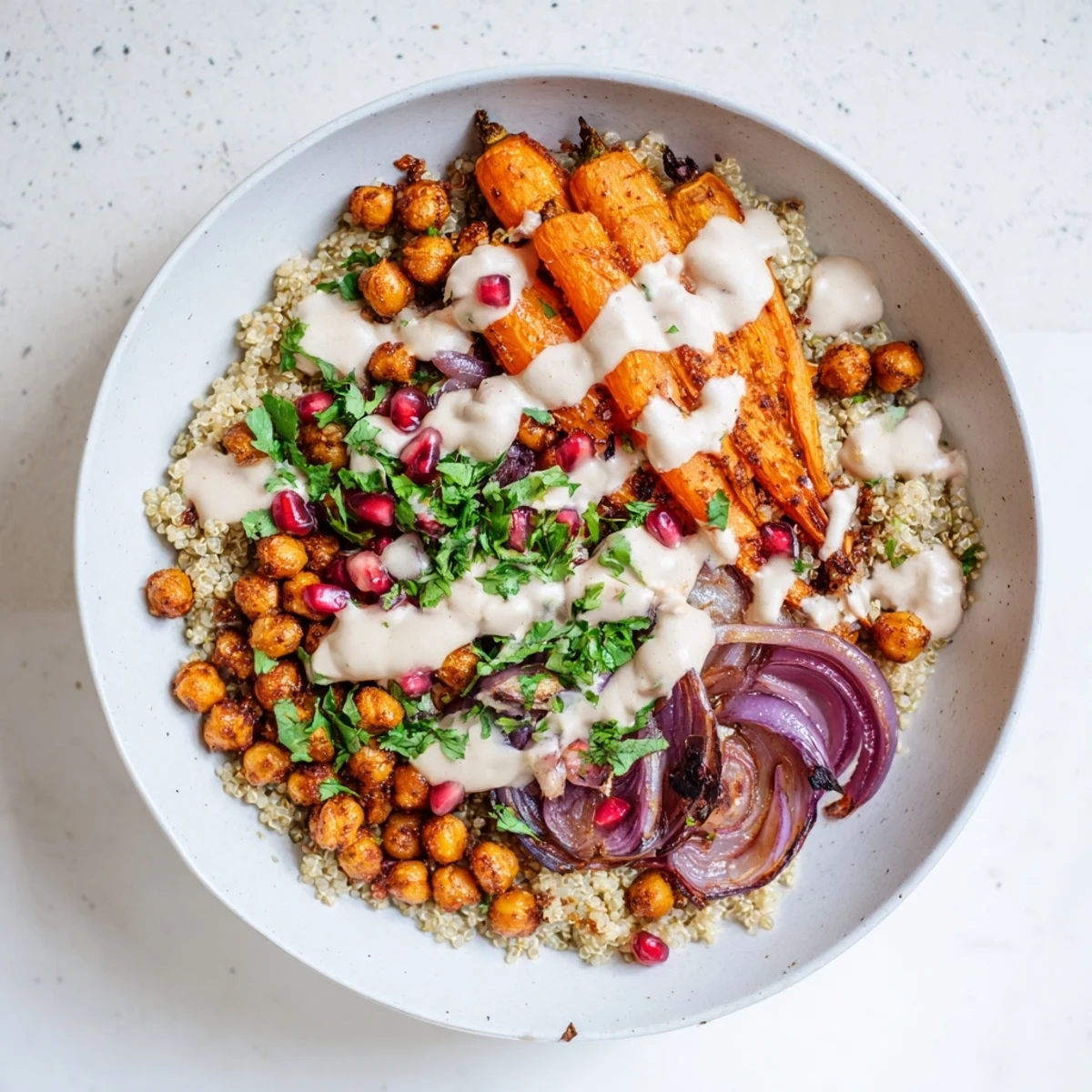 Golden roasted carrots and crispy chickpeas from the One Pan Roasted Carrot Chickpea Bowl are arranged with red onion wedges on a white plate.