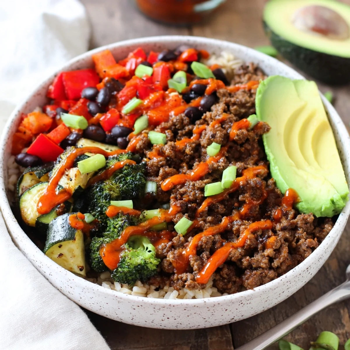 Close-up of a meal prep bowl with fluffy rice, black beans, and fresh avocado for this Viral Hot Honey Ground Beef Bowl.
