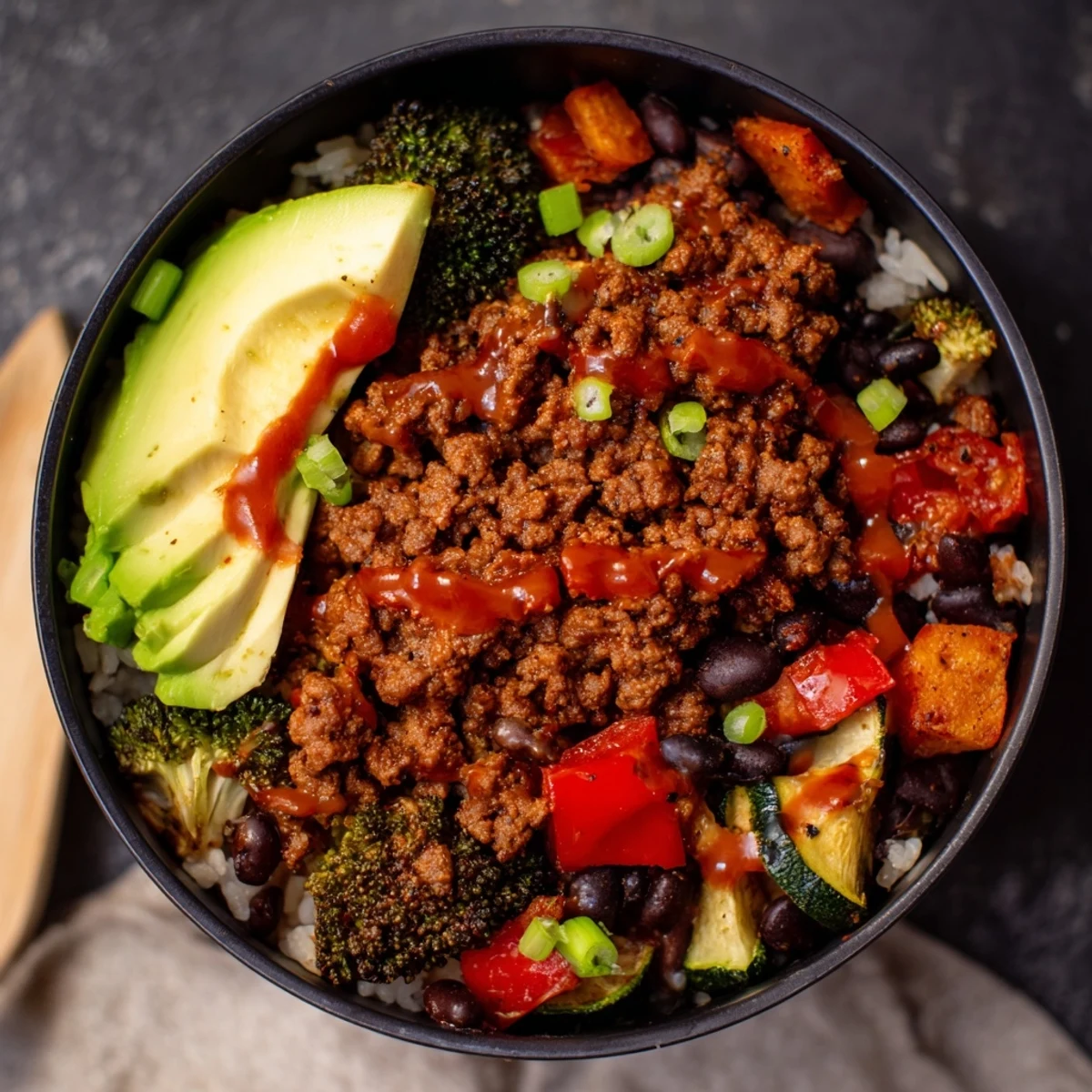 Stainless steel container holding a colorful, high-protein Viral Hot Honey Ground Beef Bowl with green onions garnish.