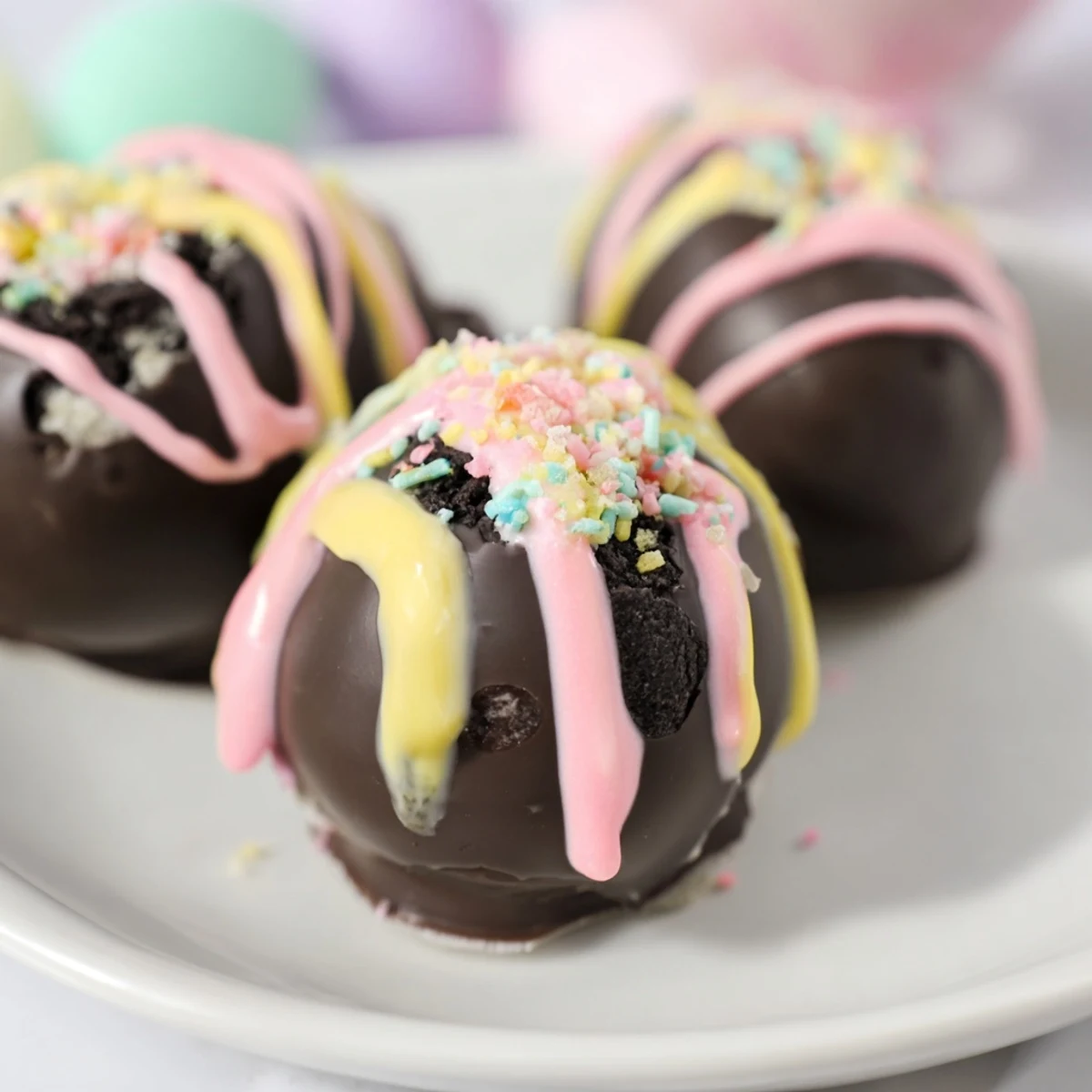 A close-up view of four homemade Easter Egg Oreo Balls with rich chocolate glaze, perfect for celebrating the holiday season.