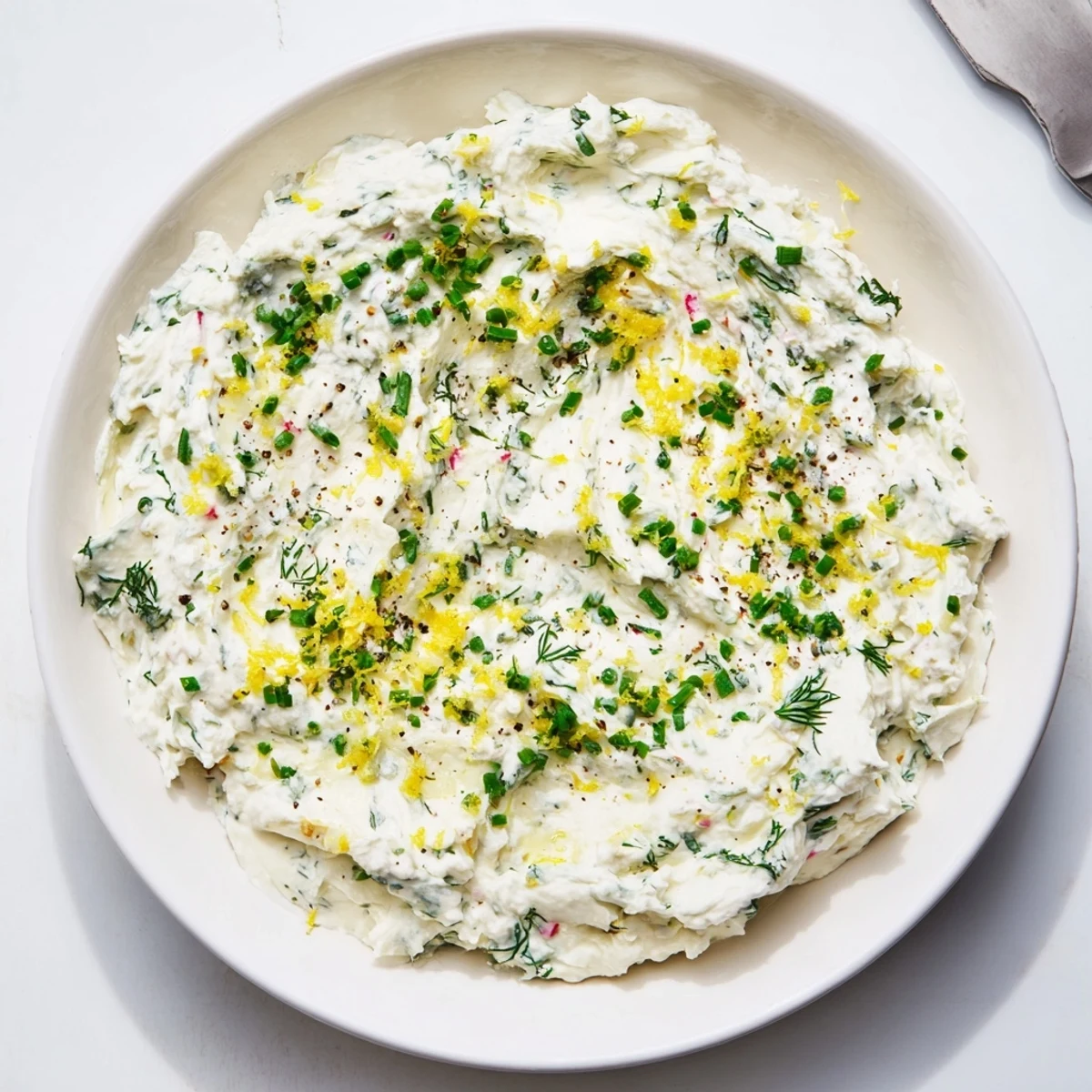 Freshly prepared Simple Easter Herb Cheese Dip in a ceramic bowl, garnished with vibrant green chives and dill.
