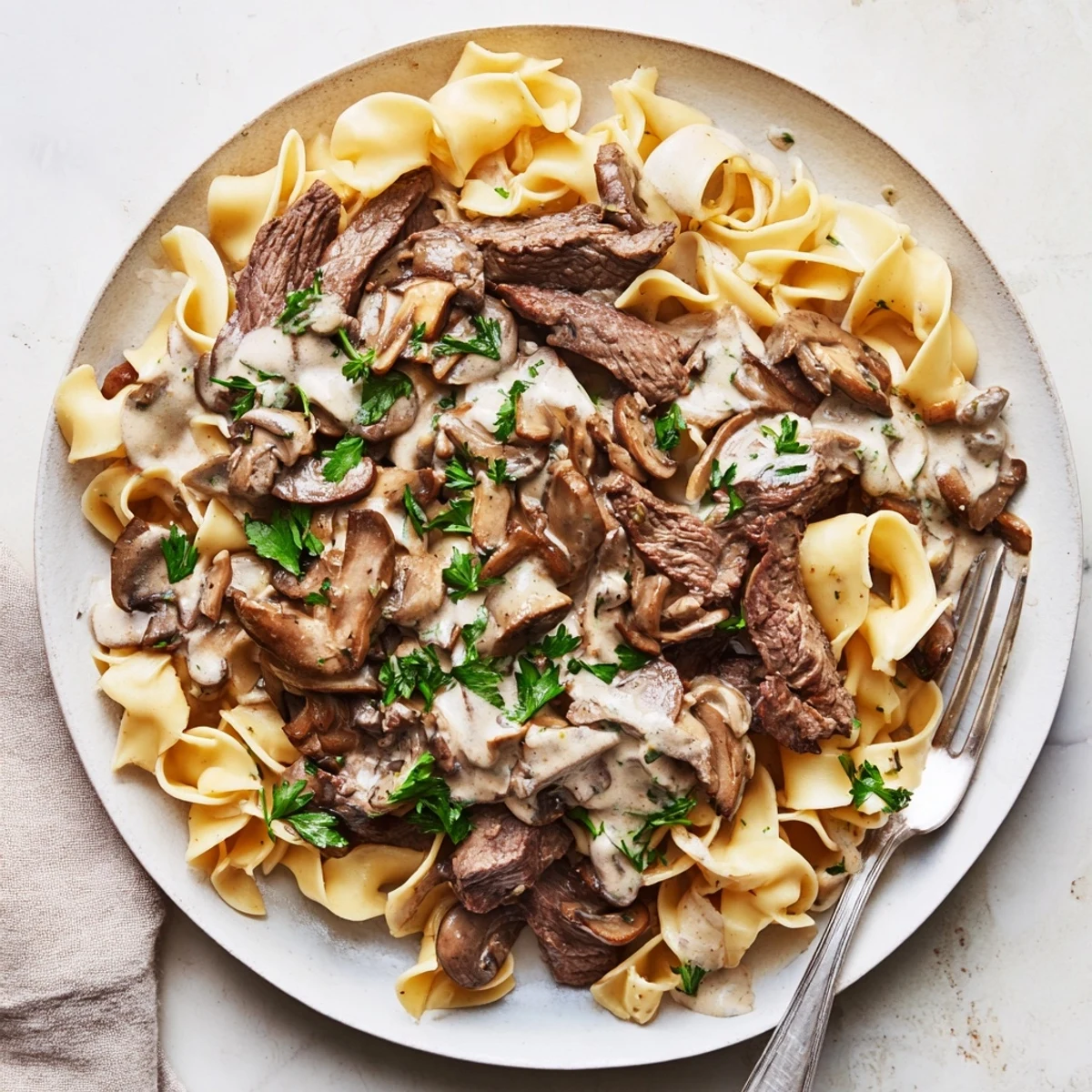Creamy beef and mushroom stroganoff served over tender egg noodles with fresh parsley garnish