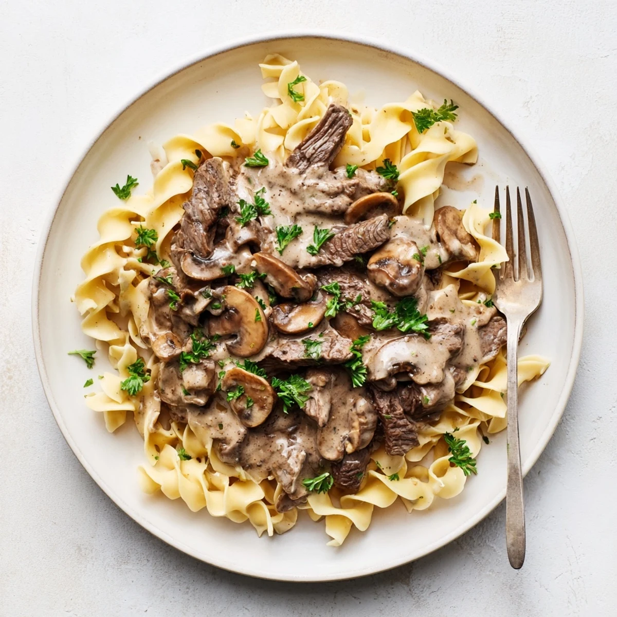 Tender beef strips and earthy mushrooms swim in rich sour cream sauce over golden egg noodles