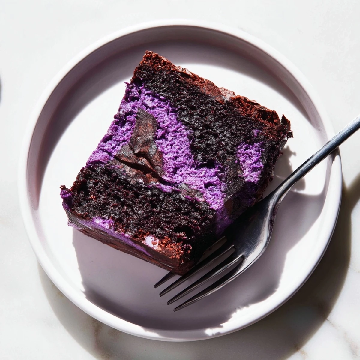 Homemade ube brownies with vibrant purple color and fudgy texture topped with chocolate sauce