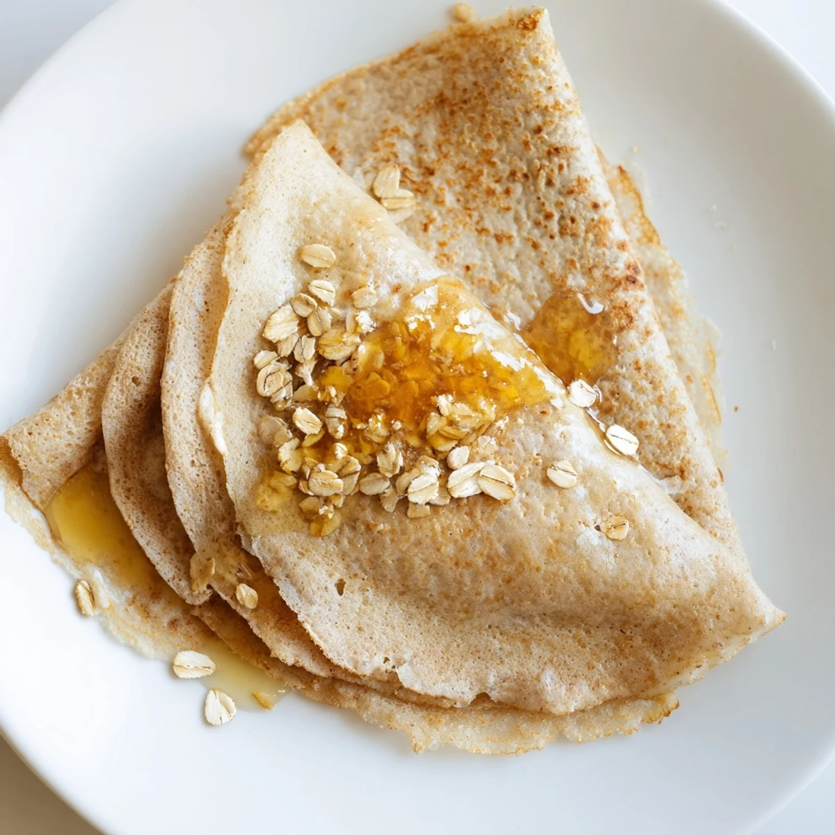 Light and tender healthy oatmeal crepes rolled with fresh berries and maple syrup