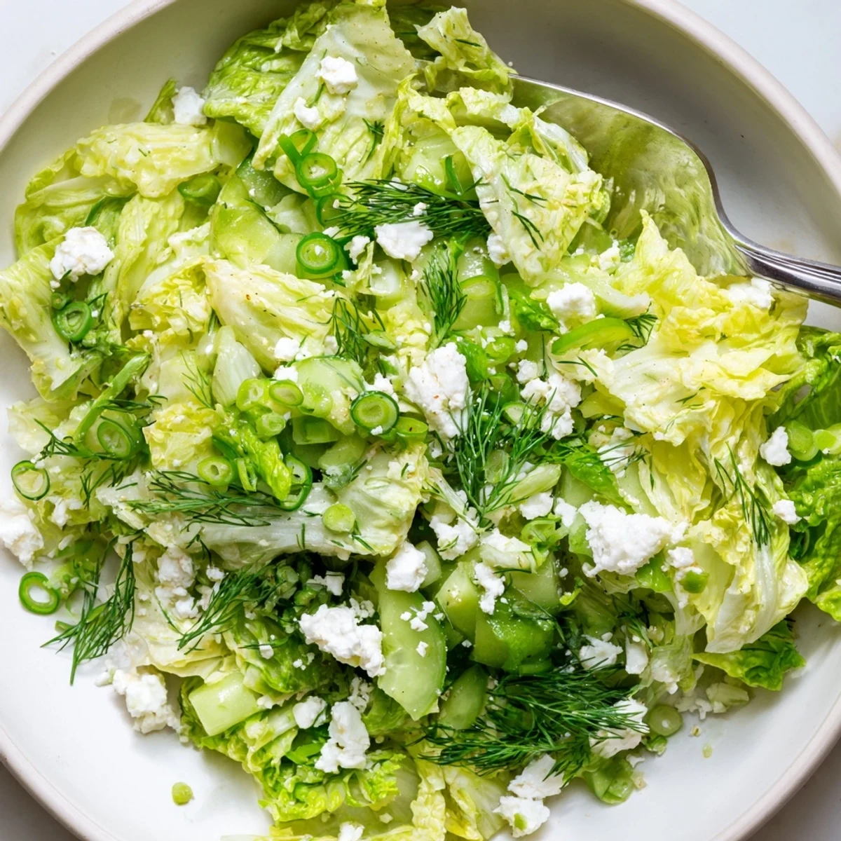 Vibrant Maroulosalata featuring shredded romaine, mint, scallions, and olive oil dressing topped with crumbled feta