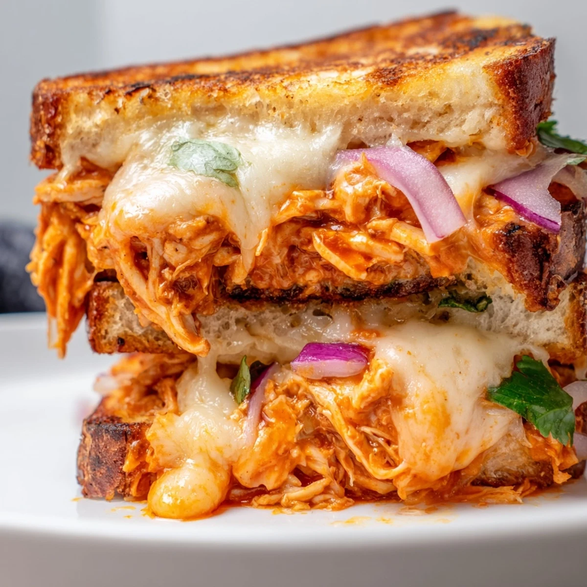 Cross section of BBQ chicken grilled cheese sandwich showing layers of melted cheese and smoky BBQ pulled chicken