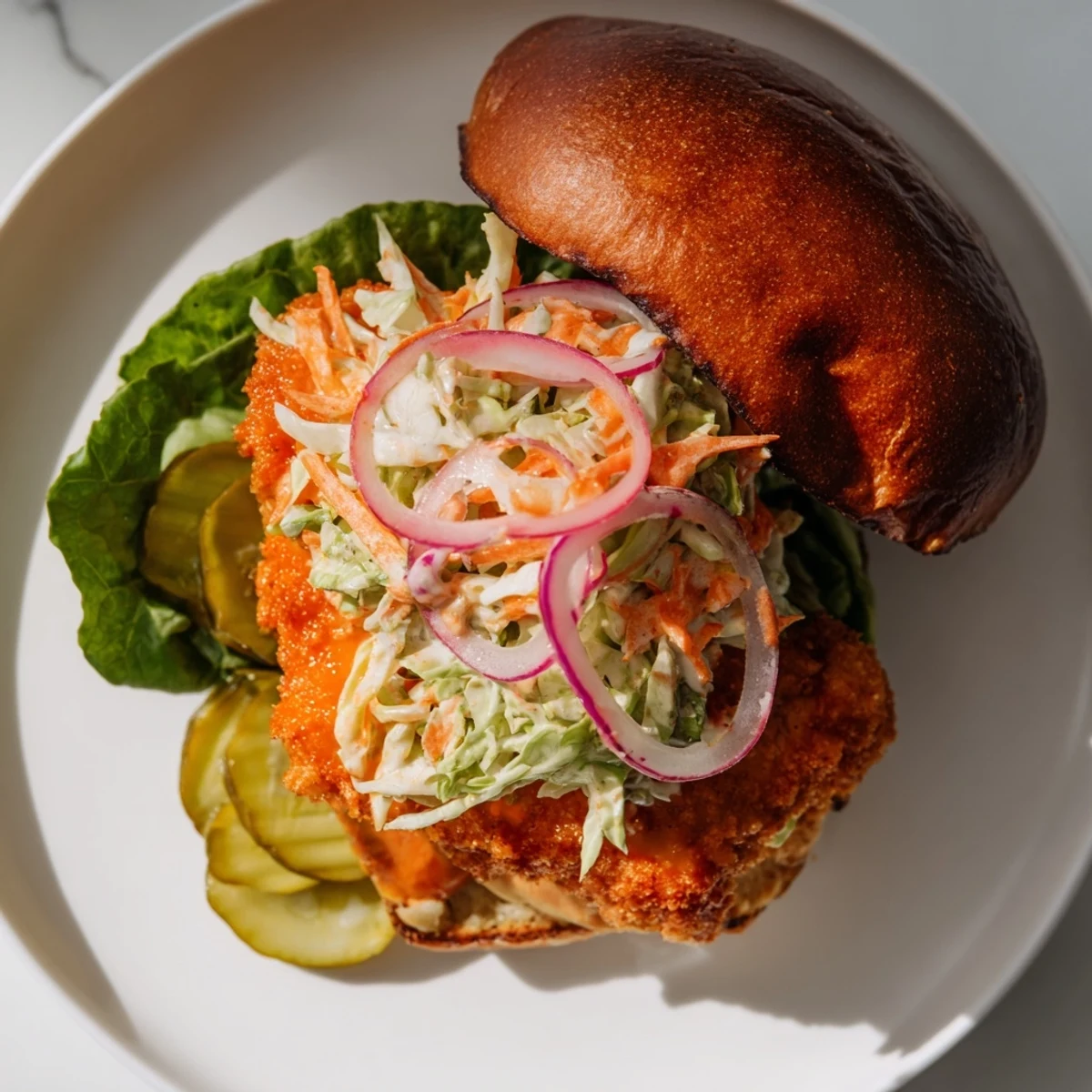 Juicy breaded buffalo chicken fillet with tangy sauce and crunchy cabbage carrot slaw inside bun