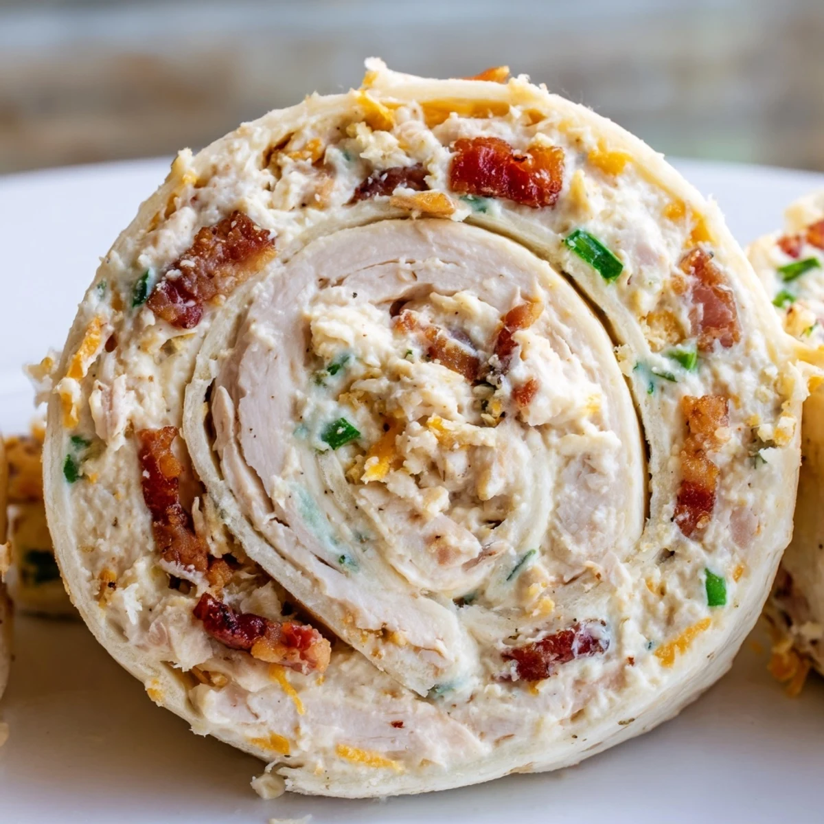 Golden spiral pinwheels stuffed with creamy crack chicken mixture and bacon crumbles on white platter