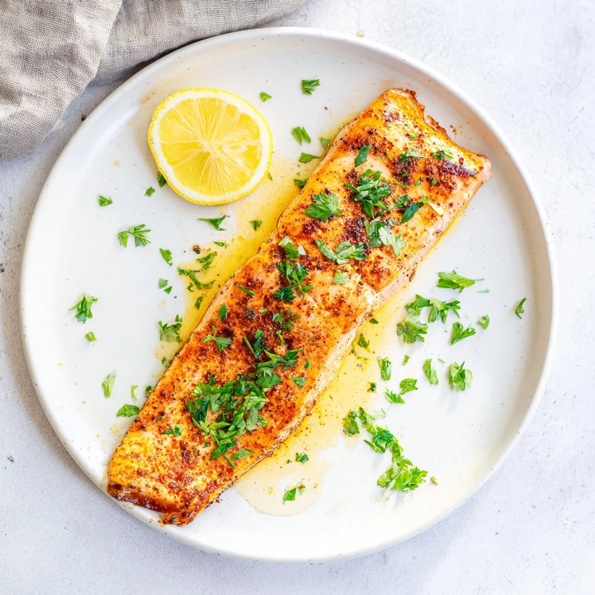 Flaky Texas Roadhouse style baked salmon with caramelized edges and fresh lemon wedges