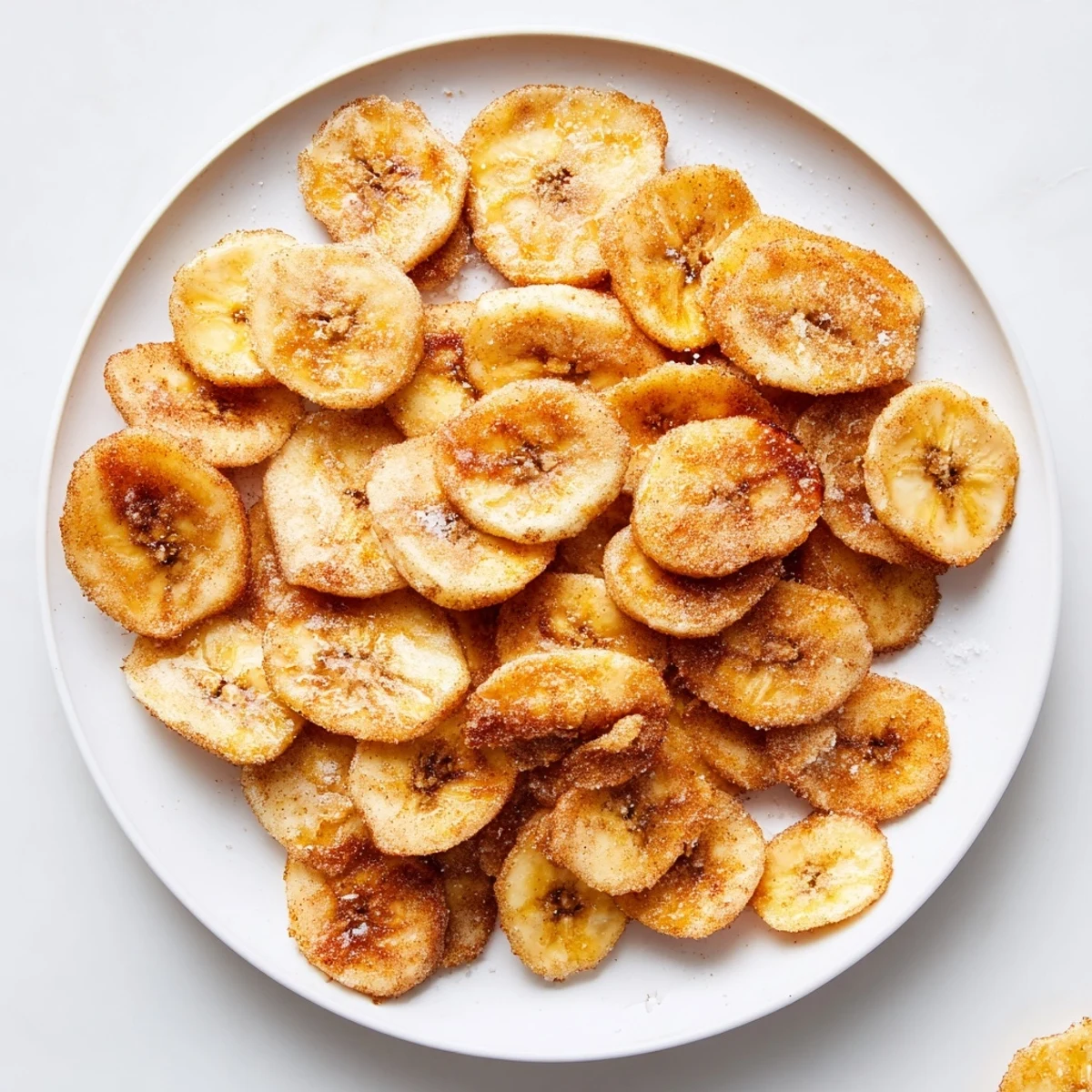 Close up of crunchy cinnamon sugar coated banana chips sprinkled with sea salt on wire rack
