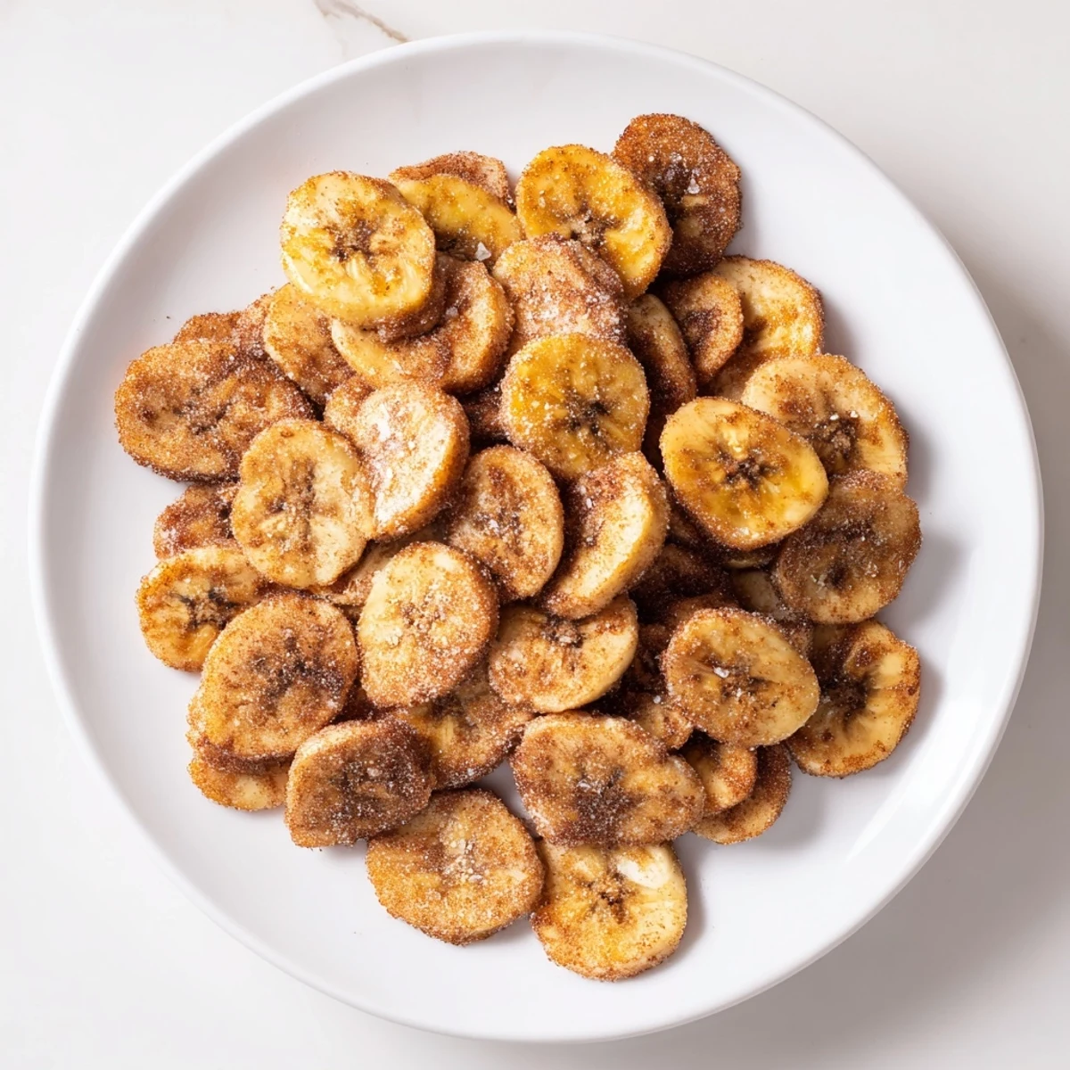 Crispy homemade banana chips coated in sweet cinnamon sugar, freshly air fried to golden perfection