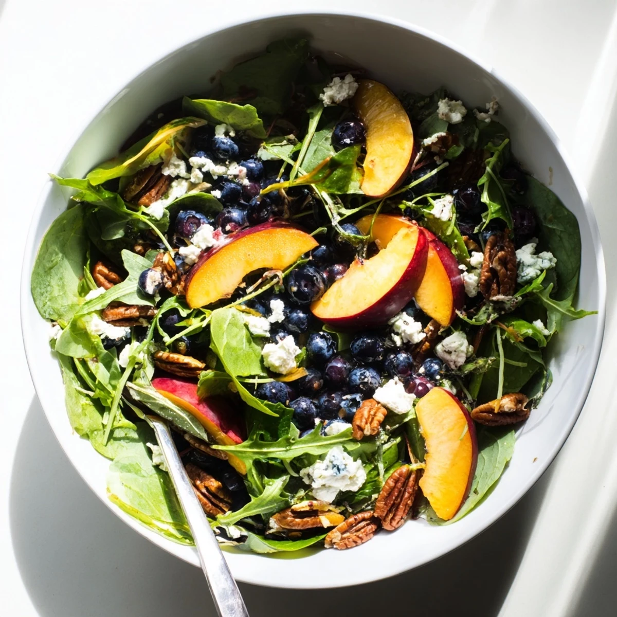Summer blueberry peach feta salad featuring ripe sliced peaches, plump blueberries, and crumbled feta over mixed baby greens
