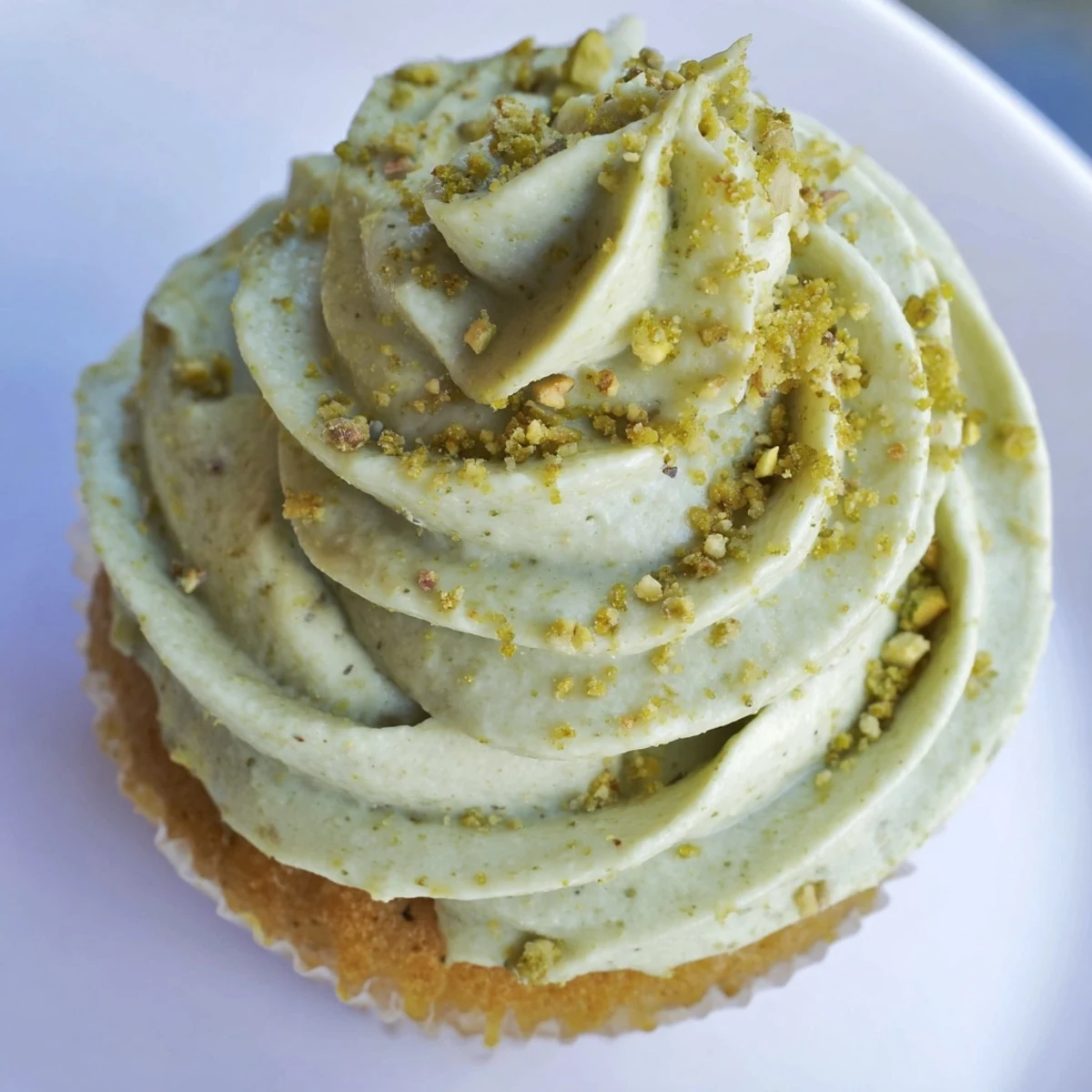 Pistachio cupcakes with swirls of creamy green buttercream topped with crushed nuts