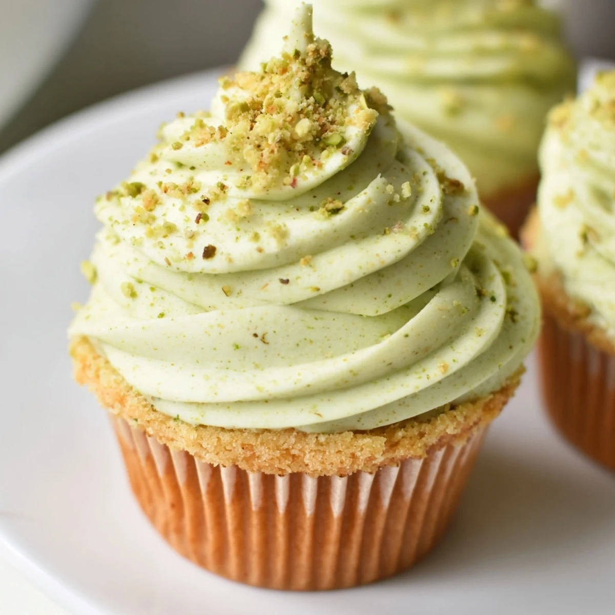 Moist pistachio cupcakes nestled in liners, crowned with fluffy nutty frosting