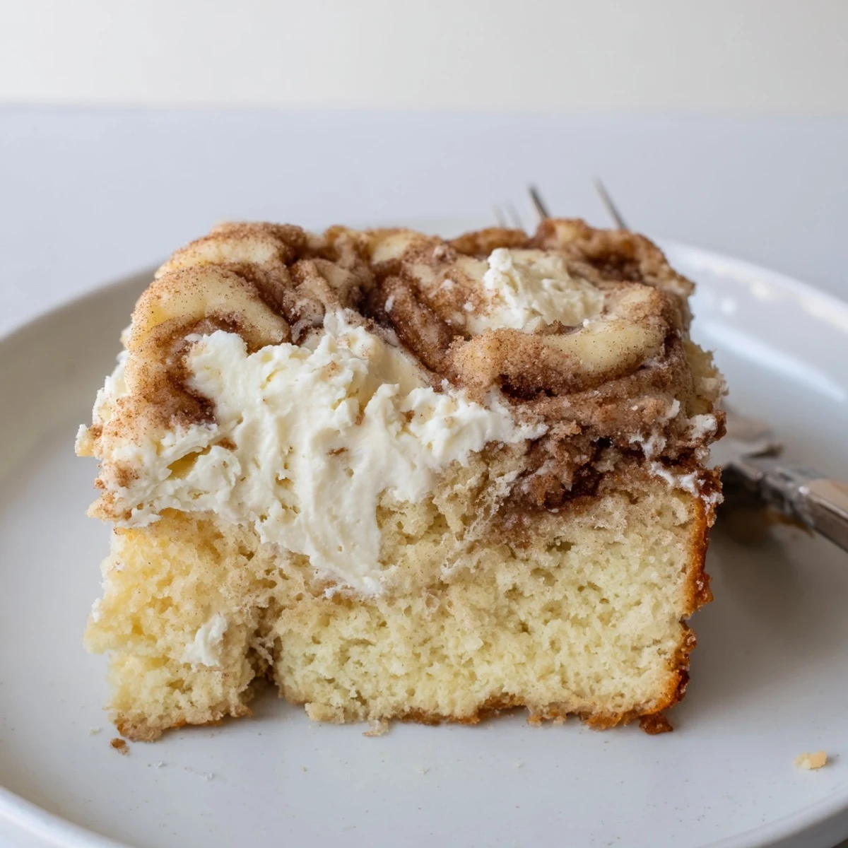Warm Cinnamon Roll Poke Cake served with melting vanilla ice cream, brunch favorite.