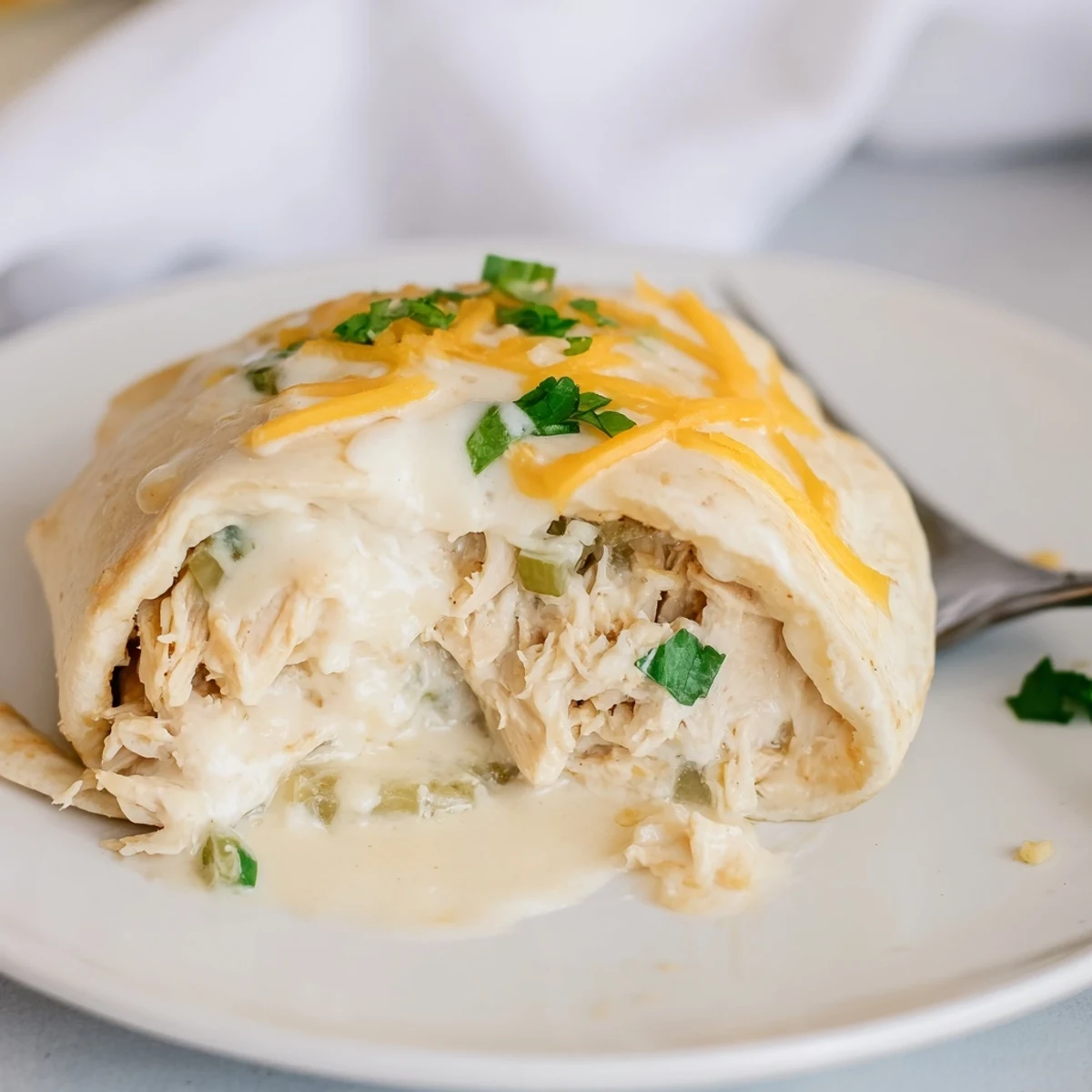Close up of White Rotisserie Chicken Enchiladas showing soft tortillas and melted cheese