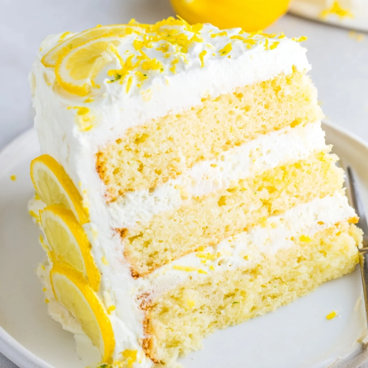 Bright yellow lemon birthday cake slice showing moist crumb and tangy citrus frosting