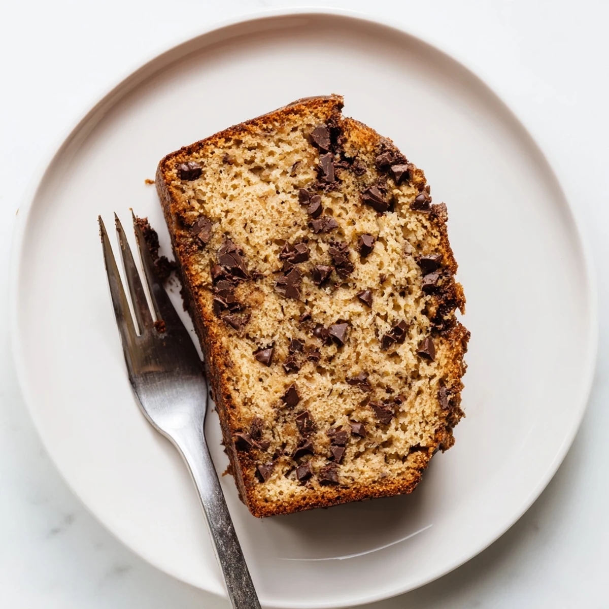 Freshly baked chocolate chip banana bread cooling on a wire rack with speckled banana peel