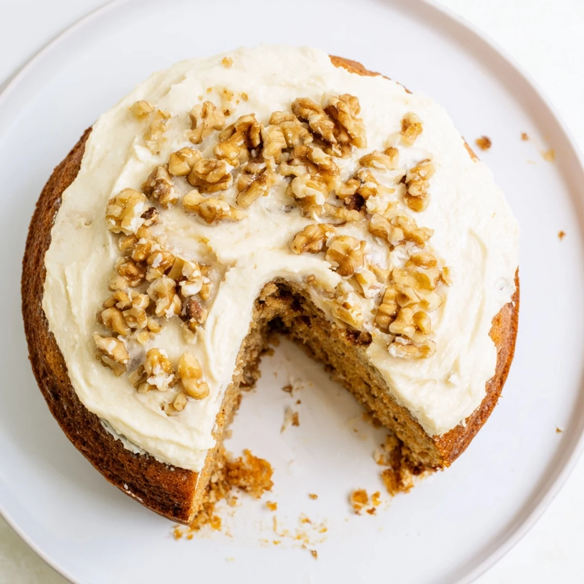 Slice of Moist Banana Cake with cream cheese frosting and chopped pecans