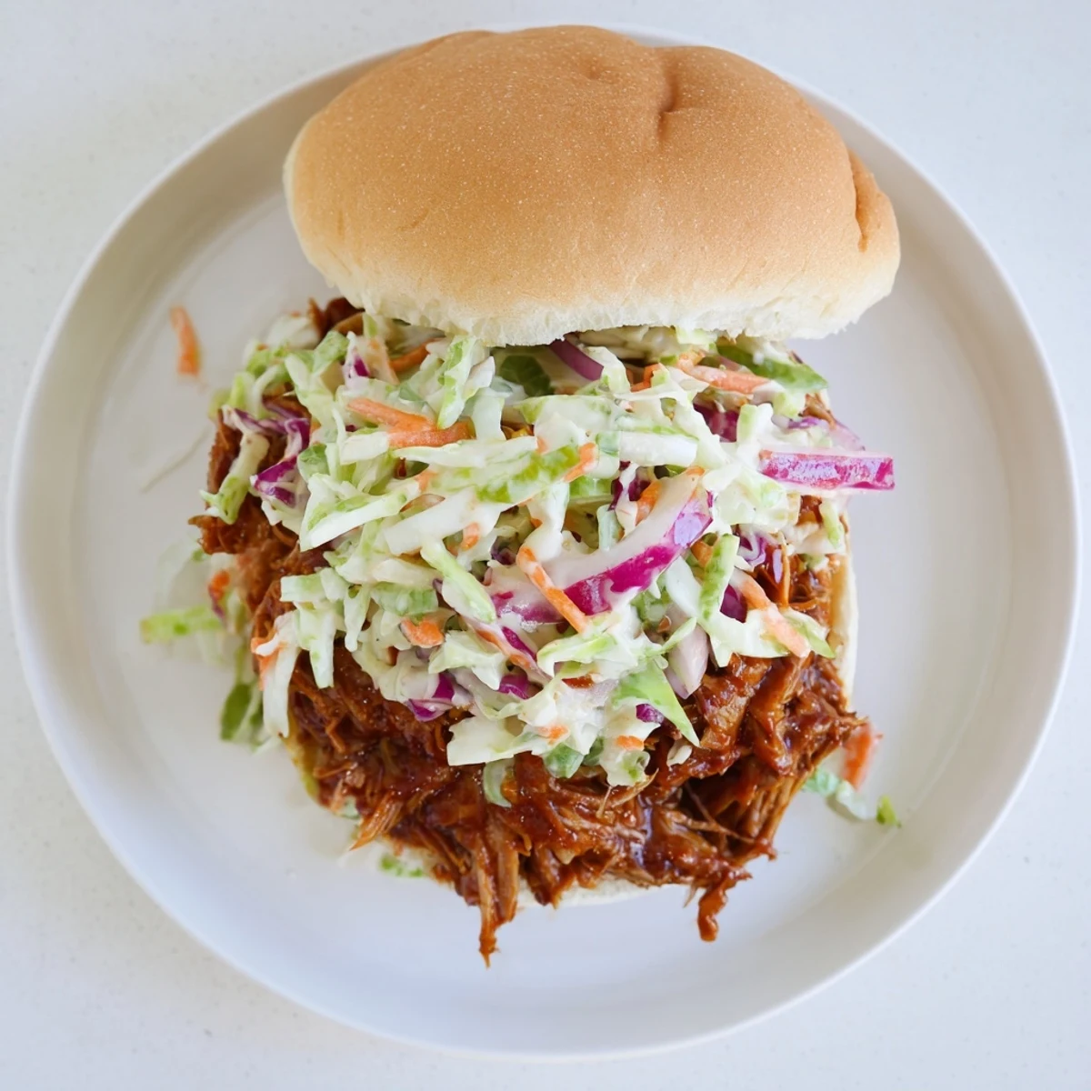 Tender shredded beef chuck roast smothered in tangy BBQ sauce topped with crunchy vegetable slaw