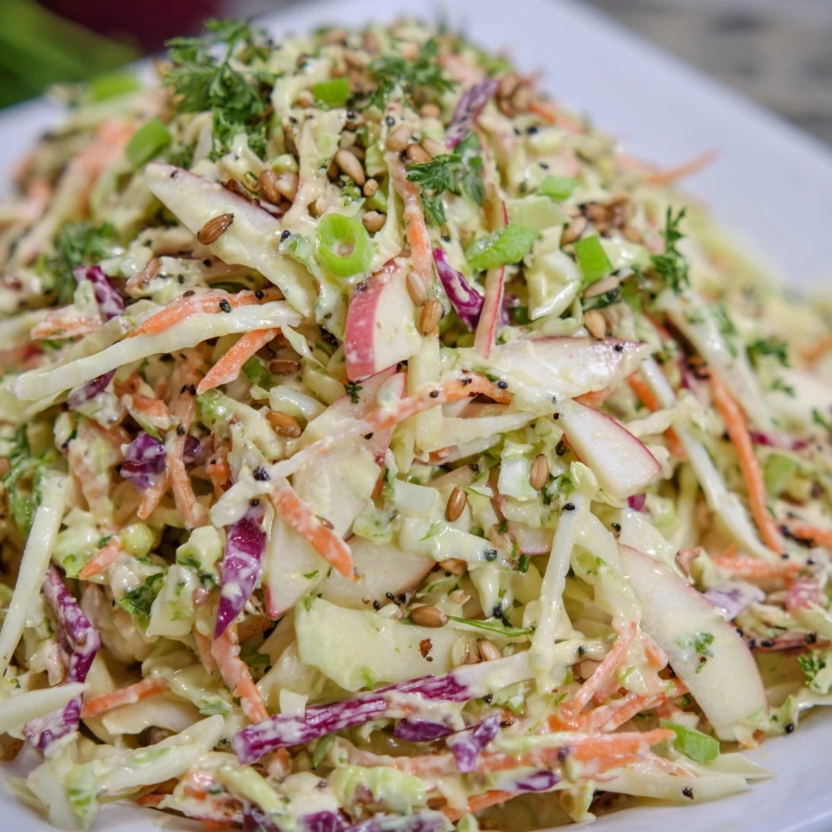 Colorful apple coleslaw piled high with crisp green and red cabbage, grated carrots, and sweet apple shreds