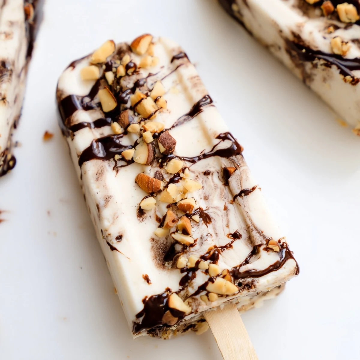 Frozen banana chocolate bliss popsicles drizzled with melted dark chocolate and topped with nuts