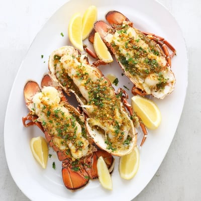 Succulent Garlic Butter Lobster Tails served with lemon wedges on a rustic plate.
