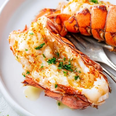 A close-up of perfectly cooked Air Fryer Lobster Tails with lemon wedges for serving.