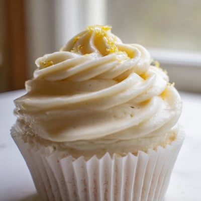 A close-up view of fluffy Elderflower Cupcakes brushed with syrup, ready for afternoon tea.